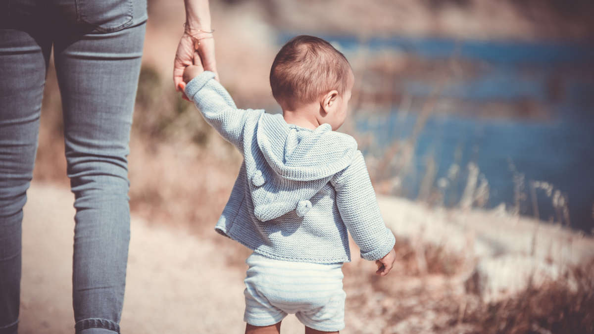 Ein kleiner Junge an der Hand einer erwachsenen Person von hinten fotografiert Ein kleiner Junge an der Hand einer erwachsenen Person von hinten fotografiert